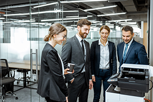 Group of business people hanging out together near the copier during a coffee break in the hallway of the big corporation