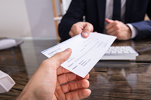 Businessperson Giving Paycheck To Colleague
