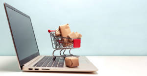 Online shopping with a full shopping cart sitting on top of a laptop