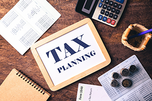 whiteboard with Tax planning text layout with a calculator. Passbook tax form and coins on wooden table for planning Money Financial Accounting Concept