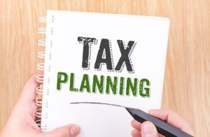 Tax Planing word on white ring binder notebook with hand holding